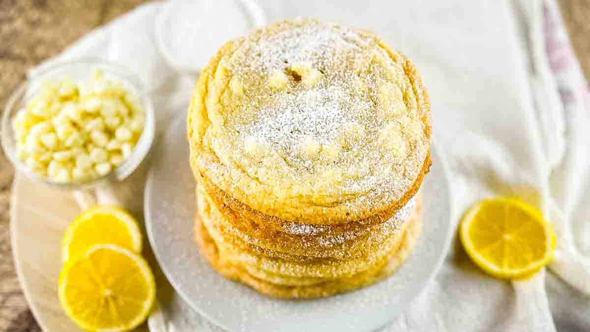 A stack of Panera lemon drop cookies stacked on a plate, dusted with powdered sugar.