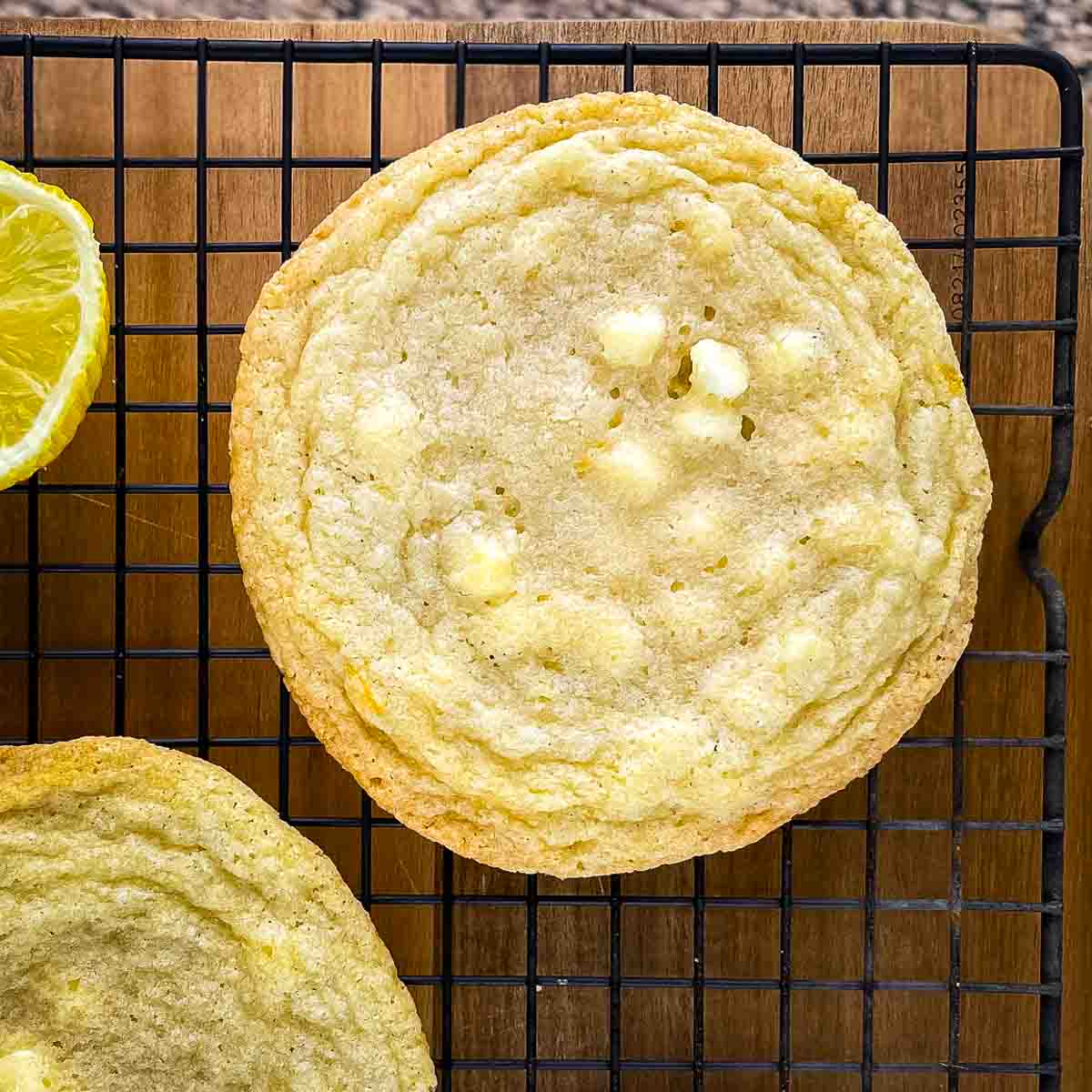 A large lemon white chocolate chip cookie in a cooling rack.
