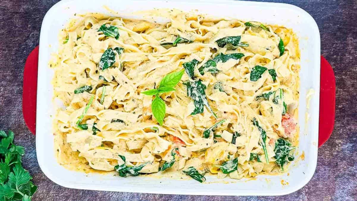 A casserole dish of creamy Boursin tomato pasta topped with fresh basil and a sprinkle of Parmesan cheese.