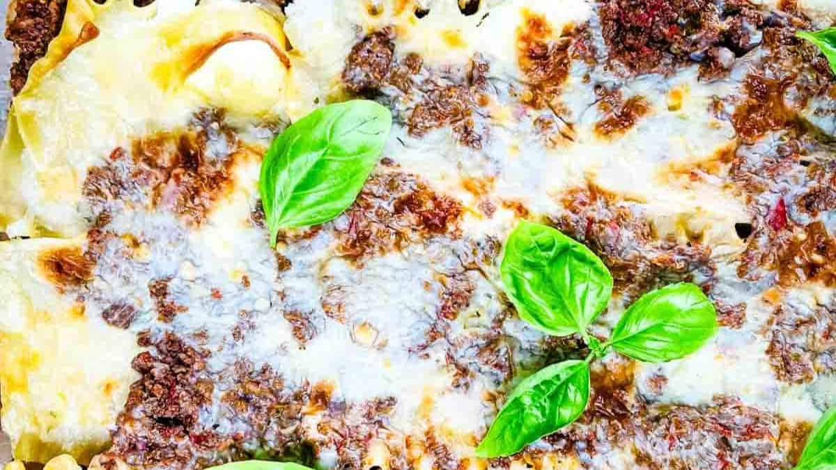 A slice of classic Lasagna with Ricotta Cheese, layered with meat sauce, ricotta, and melted cheese, garnished with fresh basil.