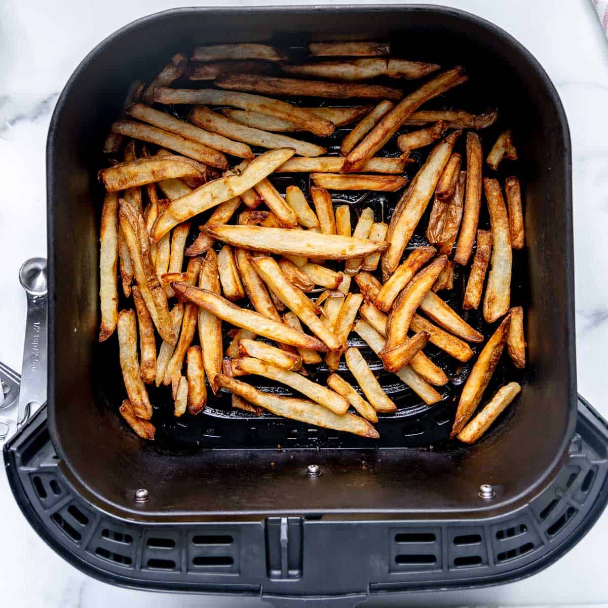 Golden brown fries in the air fryer basket.