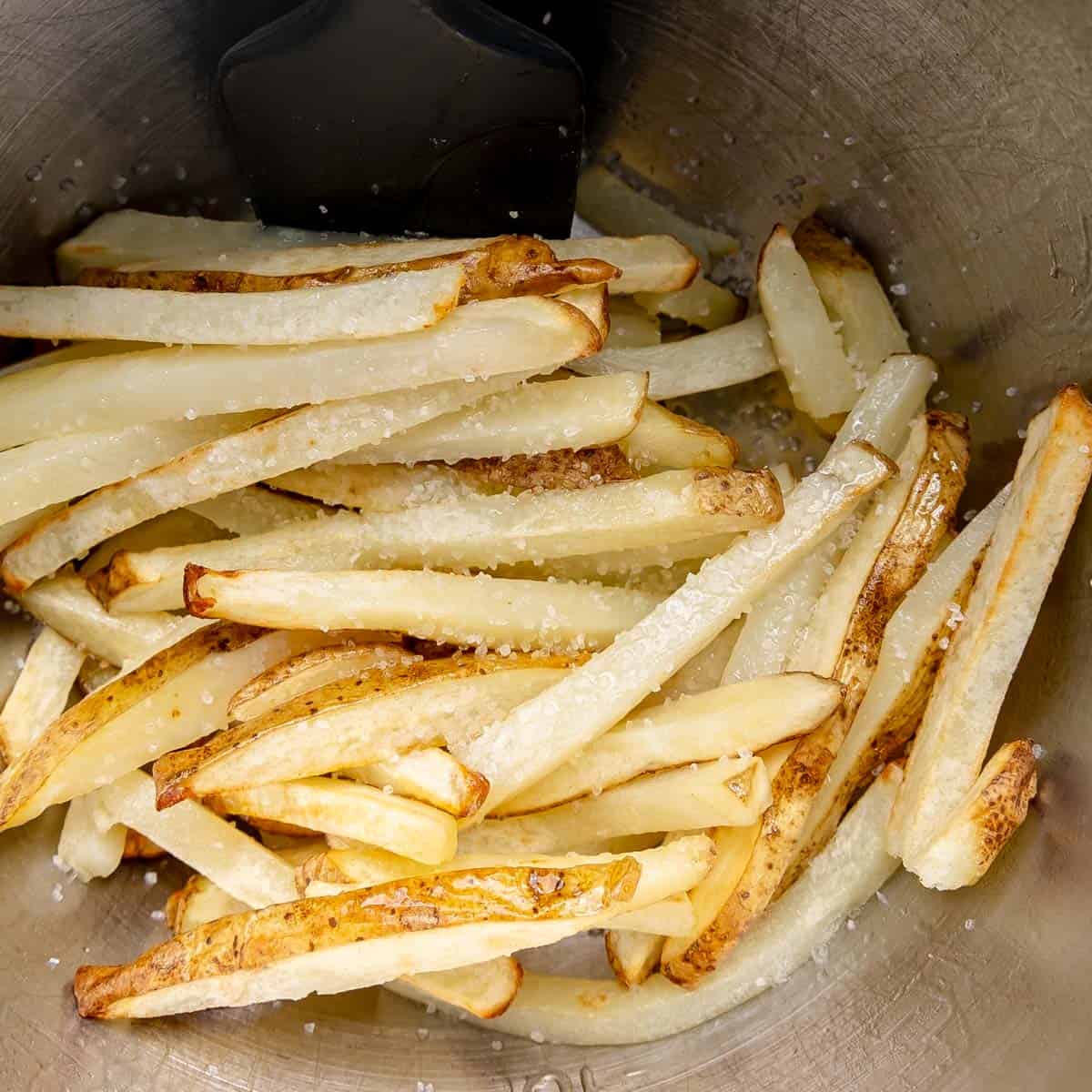 Salted french fries in a metal bowl.