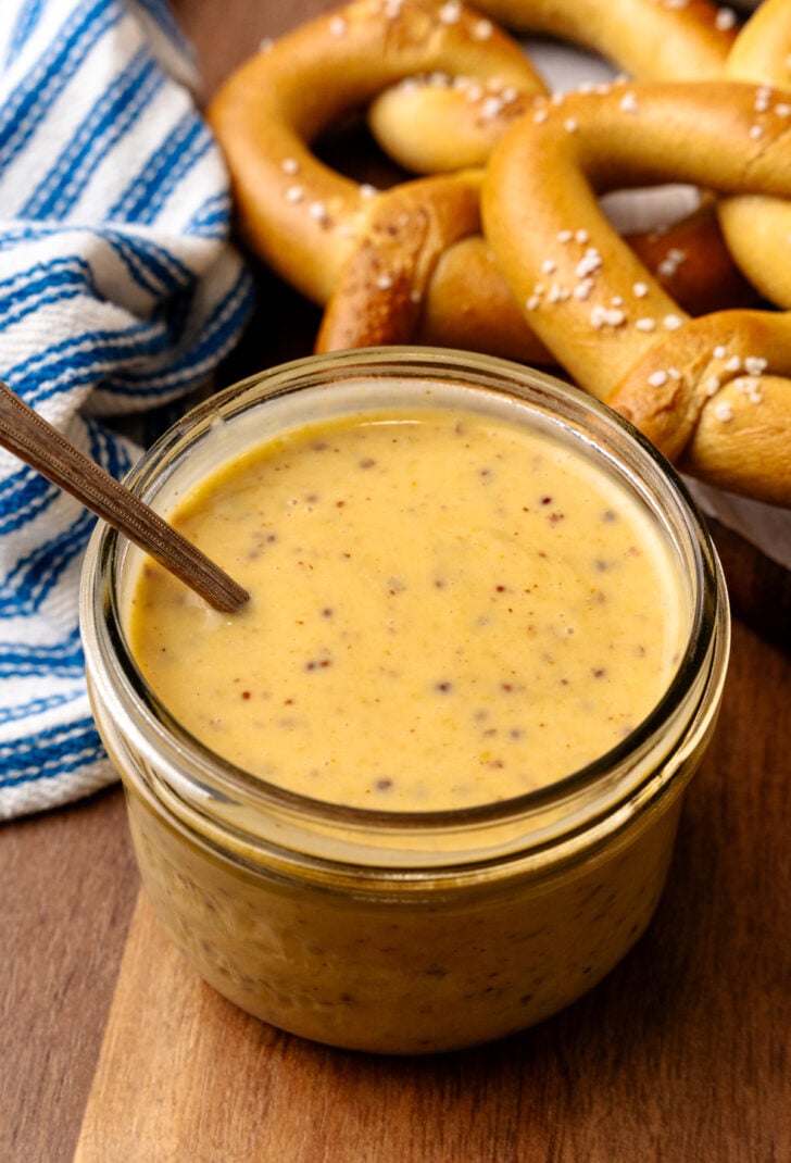 Honey mustard in a small glass jar served with a spoon.