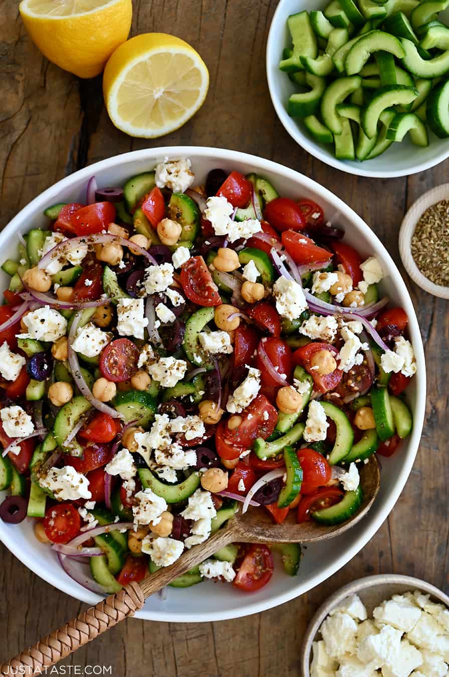 A large serving bowl containing Greek cucumber tomato salad with crumbled feta cheese